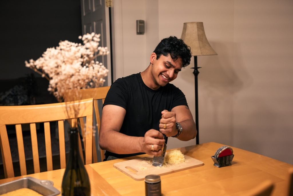 Young man grating cheese at a table
