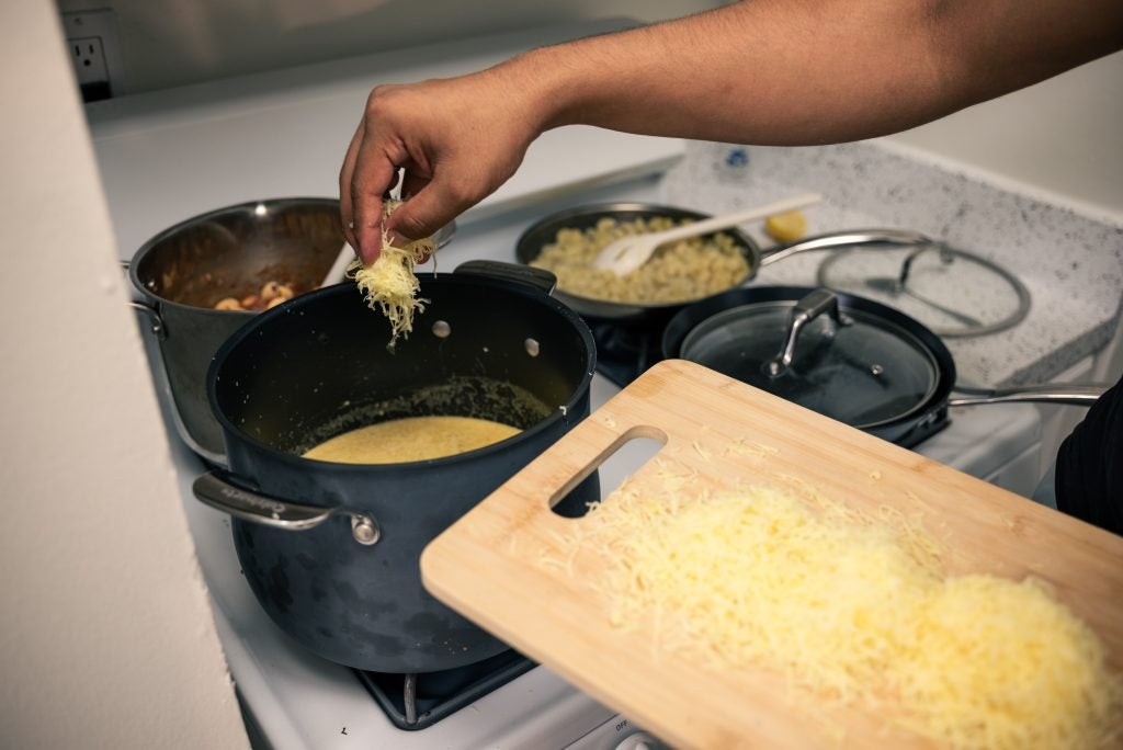 hand dropping cheese into a soup