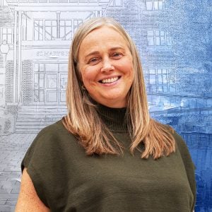 A woman smiles in front of a textured blue background of a building