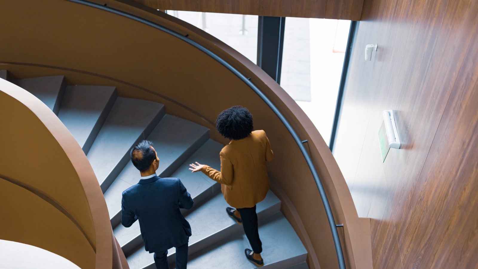 Two people walk up a staircase in an office building