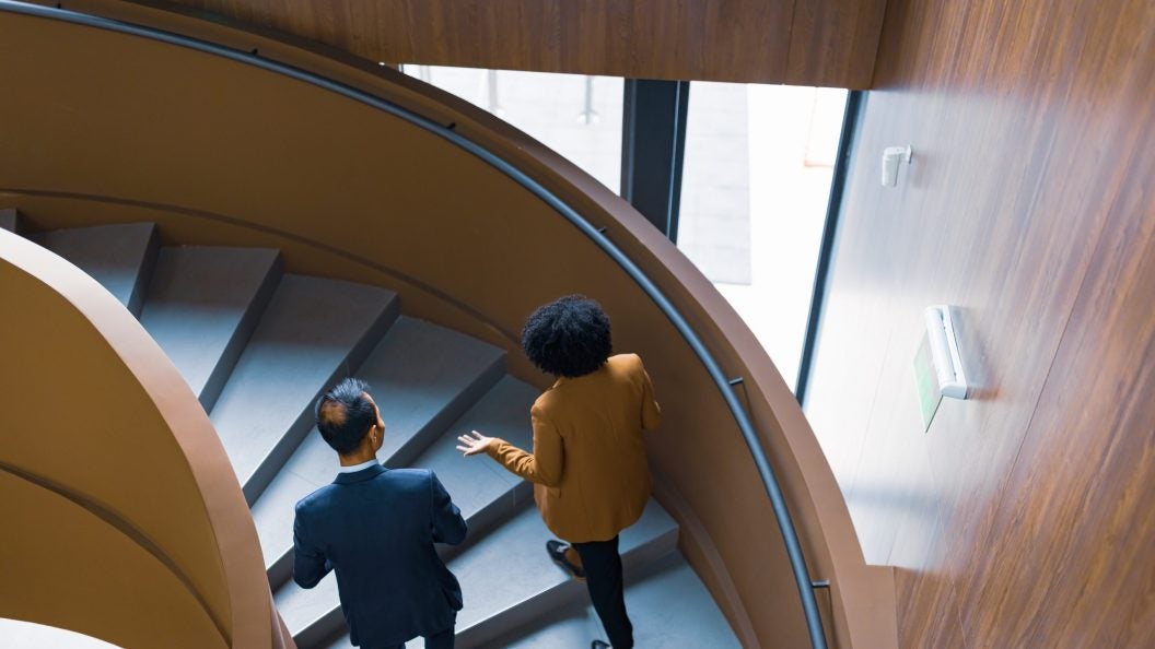 Two people walk up a staircase in an office building