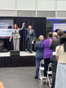 Chuck Schumer on stage raising another woman's hand in celebration