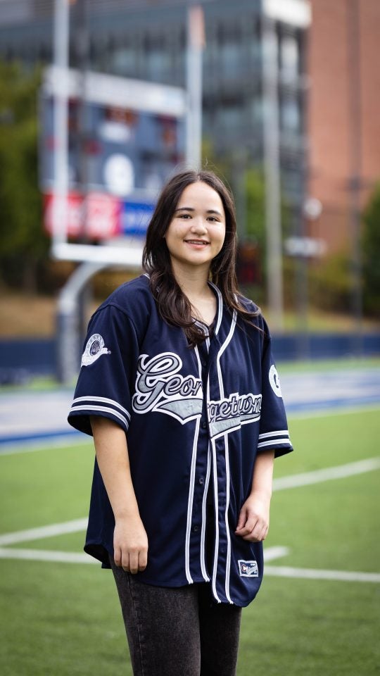 Juliette in a blue GU jersey on a football field