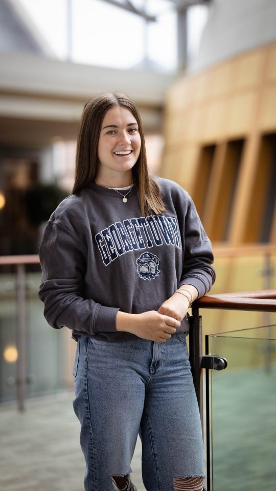 Sarah in gray GU sweatshirt in the Hariri building