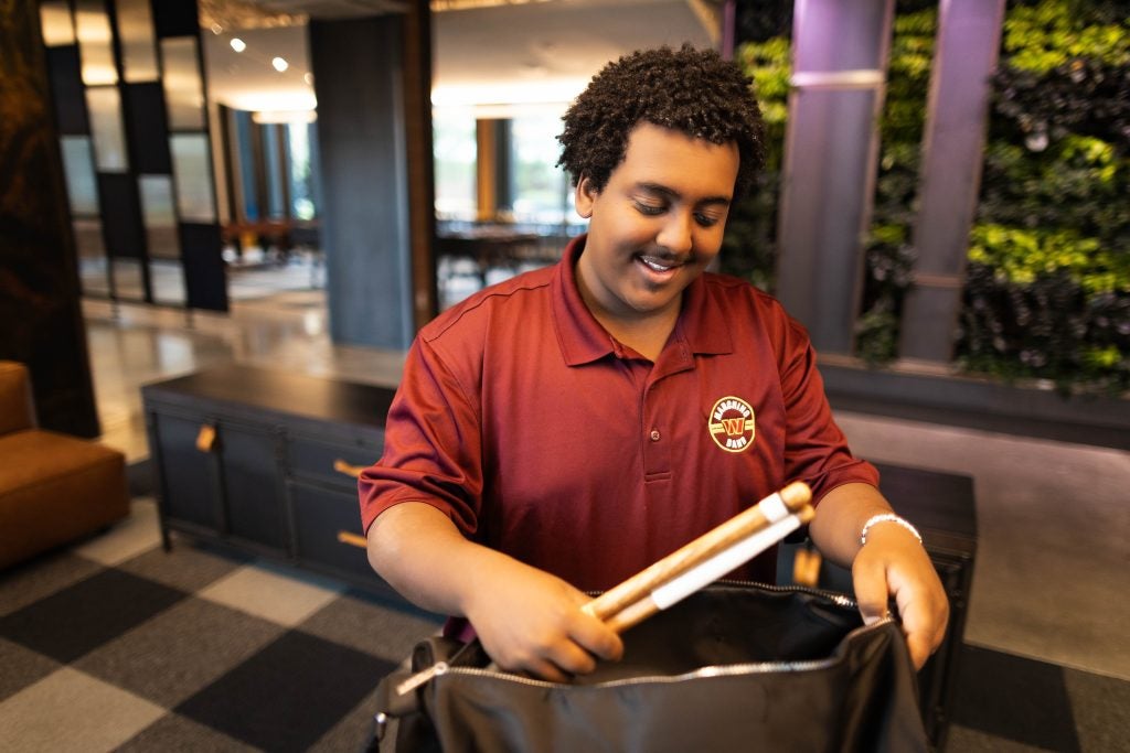 Young Black man takes drumsticks out of a bag