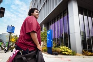 Young Black man carrying a shoulder bag outside
