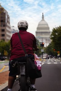 Young Black man on a bike with a helmet riding toward the Capitol