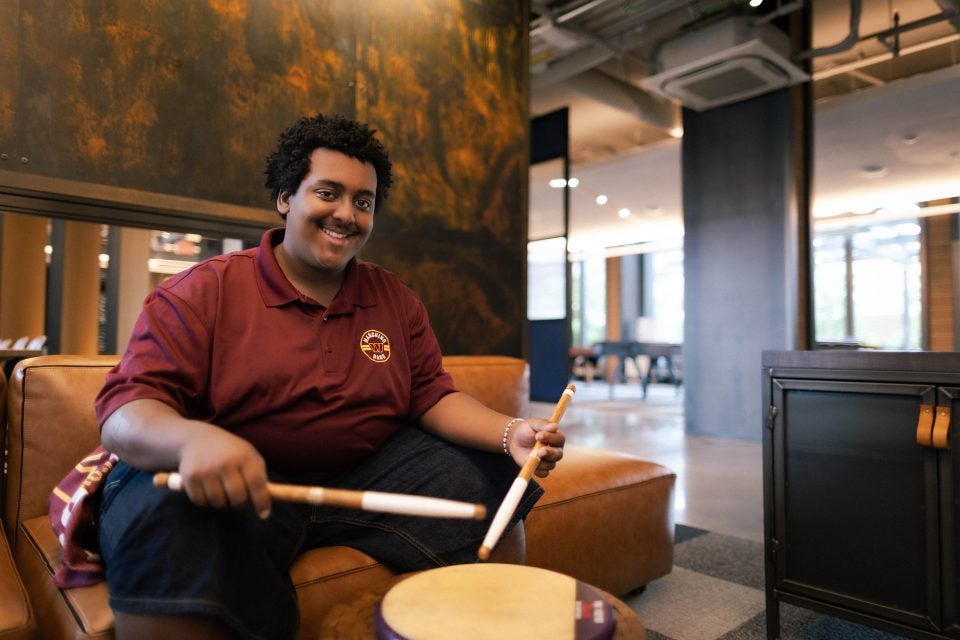 Young Black man smiling with a drum set