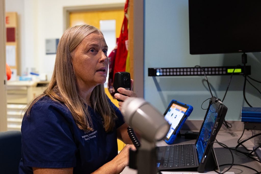 A nurse speaks into a microphone in a control room