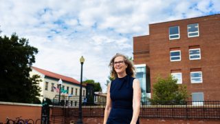 A woman in a blue dress smiles as she walks on a patio
