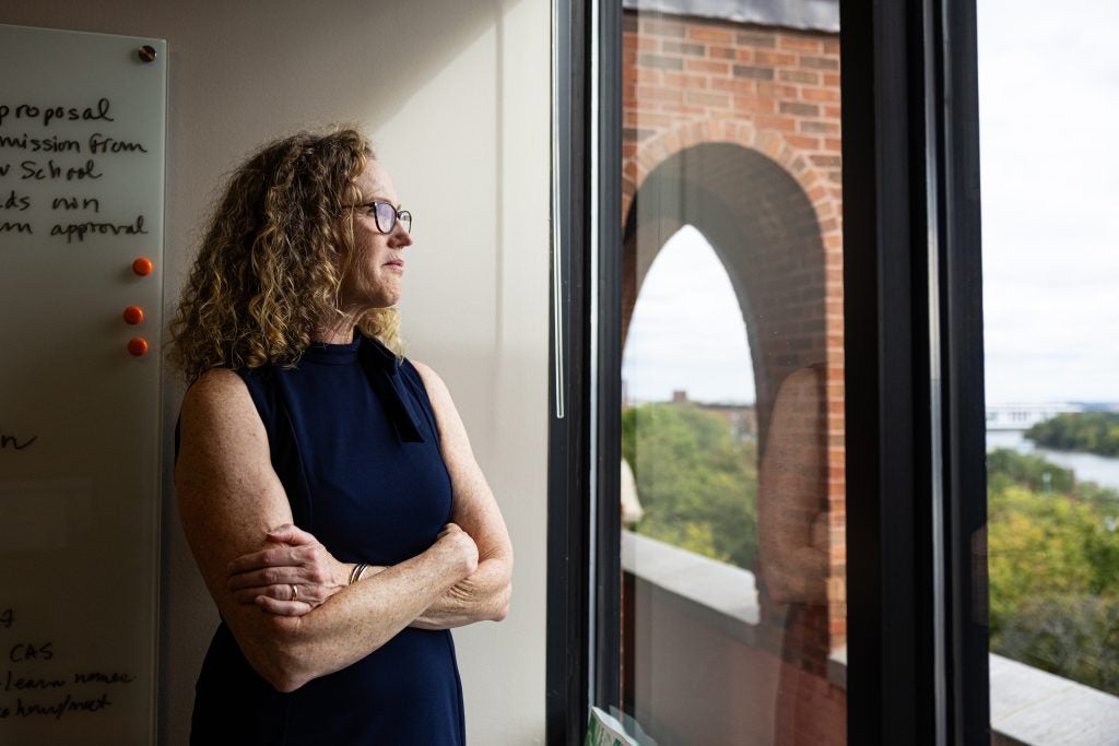 A woman with blonde curly hair smiles out the window
