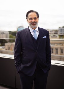 Georgetown President-Elect Eduardo Peñalver smiles on a balcony in a suit and tie