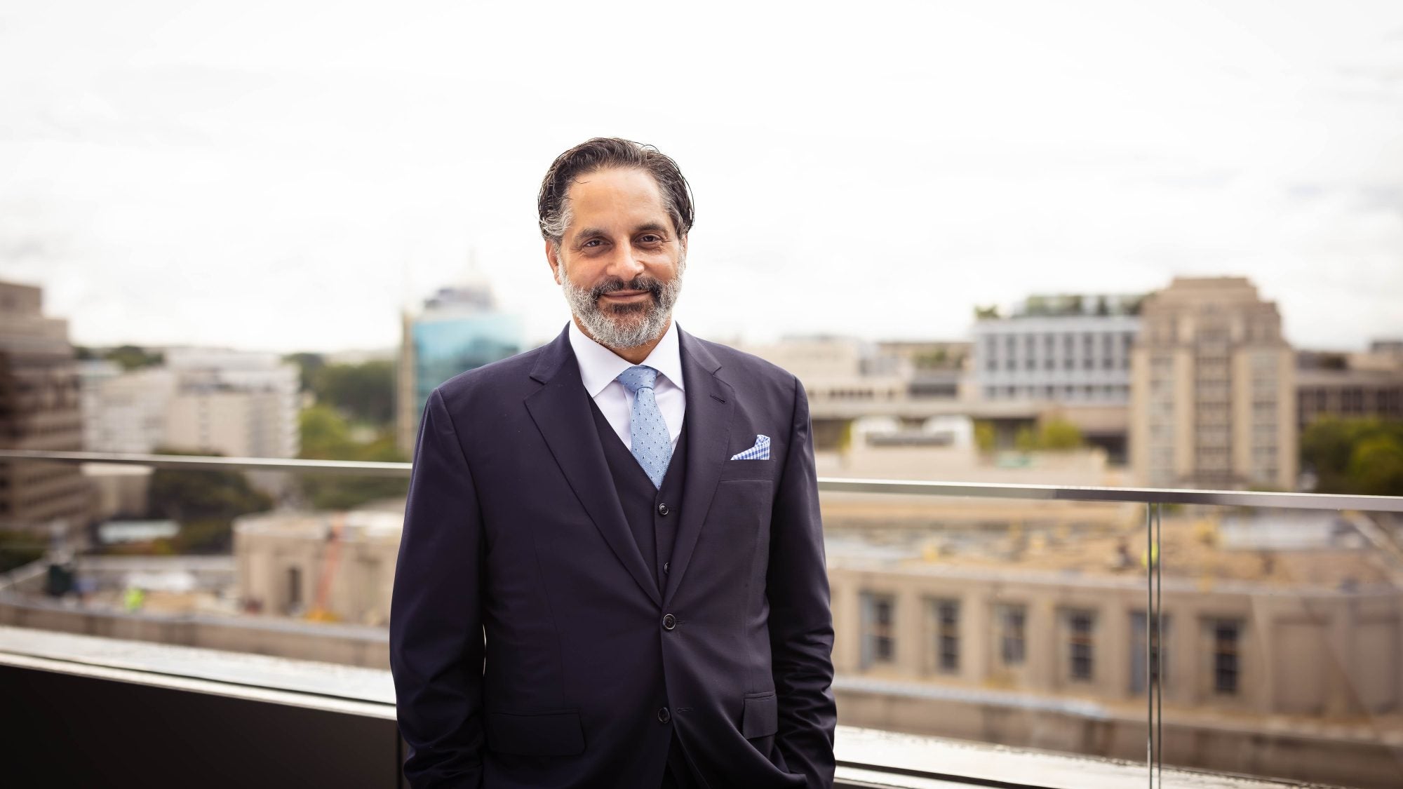 A man in a suit and tie stands on a balcony