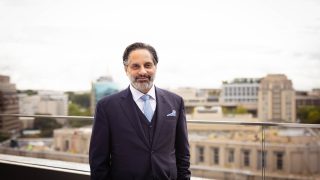 A man in a suit and tie stands on a balcony