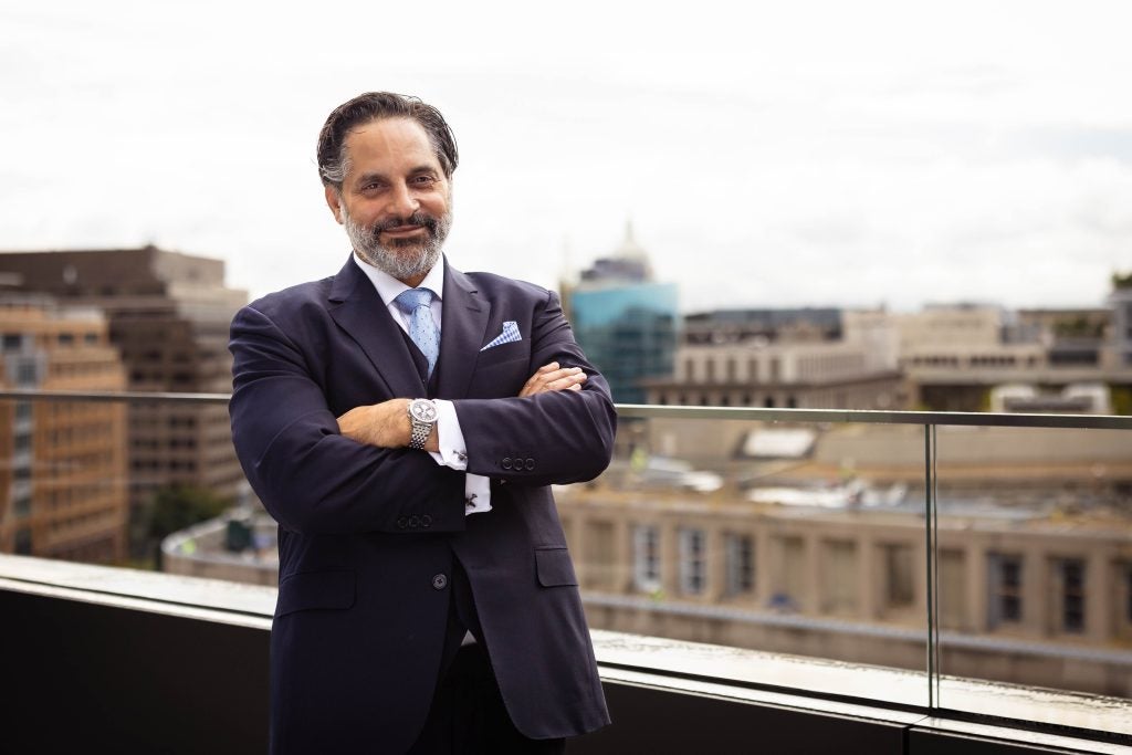 Eduardo Peñalver crosses his arms and smiles while standing on a balcony