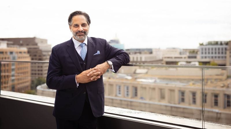 A man stands on a balcony in a suit