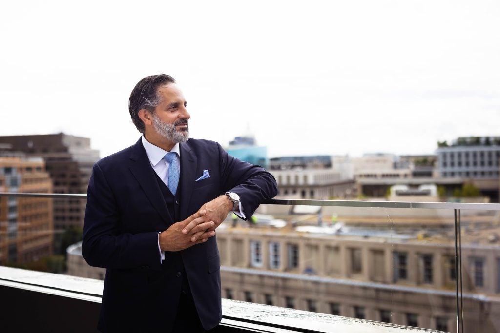 A man wearing a suit looks out over a balcony
