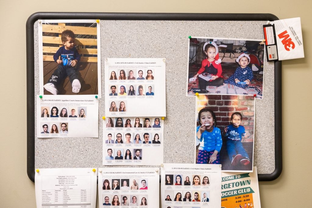 A bulletin board with photos of a staff member's kids and students in Georgetown Law's clinical program