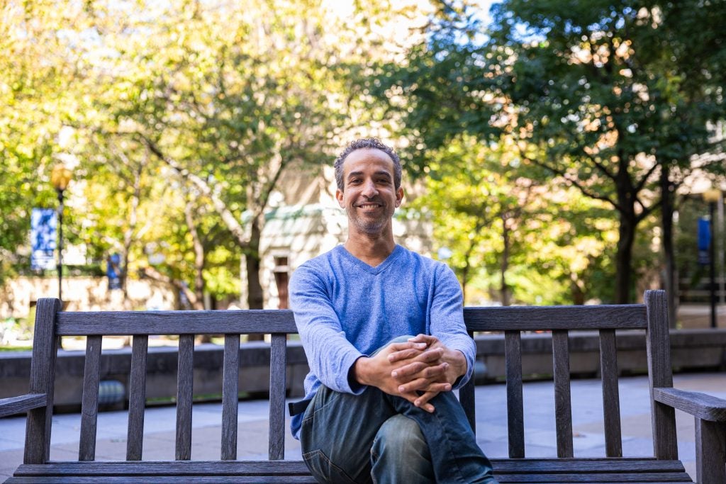 A man sits on a park bench and smiles