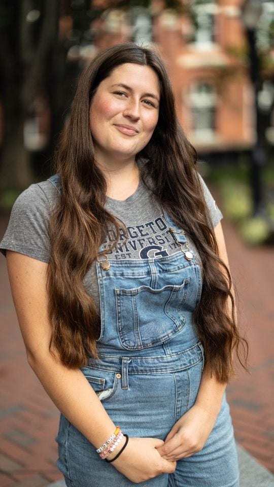 Sydney in a gray GU t shirt and in denim overalls