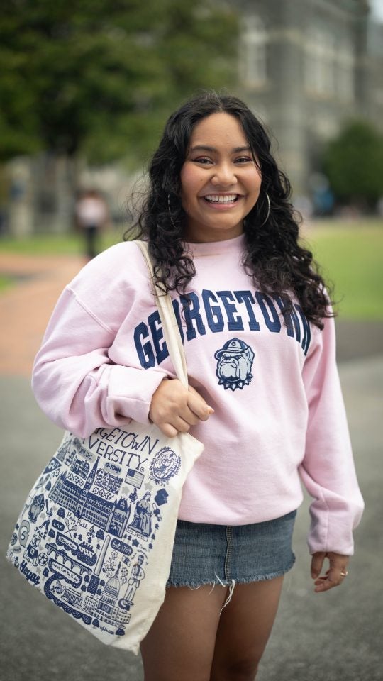 Mara in a pink GU sweatshirt with a GU tote bag