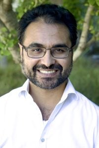 A headshot of a Jesuit priest dressed in a white collared shirt and glasses