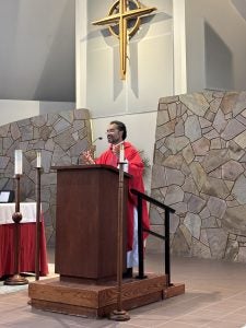 A priest stands on the altar of a Catholic Church preaching