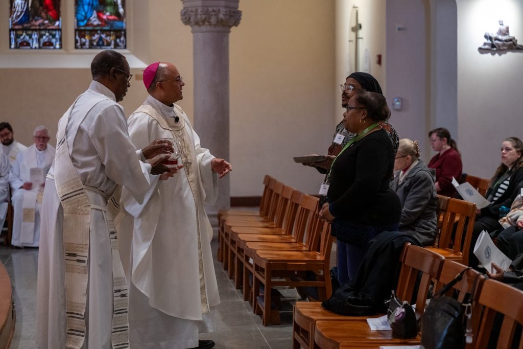 A group of clergy speak to two people in a church
