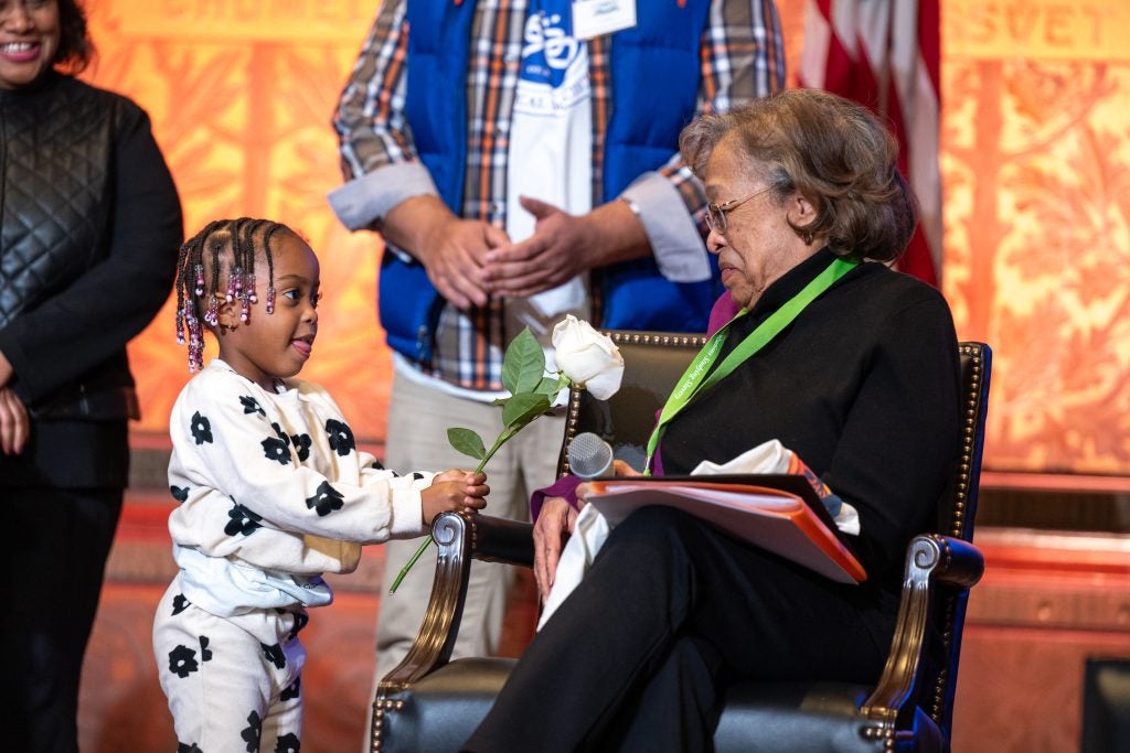 An older Black woman speaks to a young child on stage in Gaston