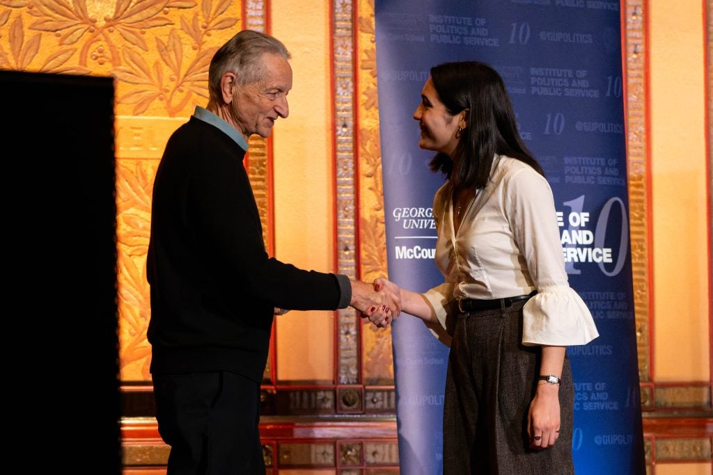 Geoffrey Hinton shakes hands with a woman on stage