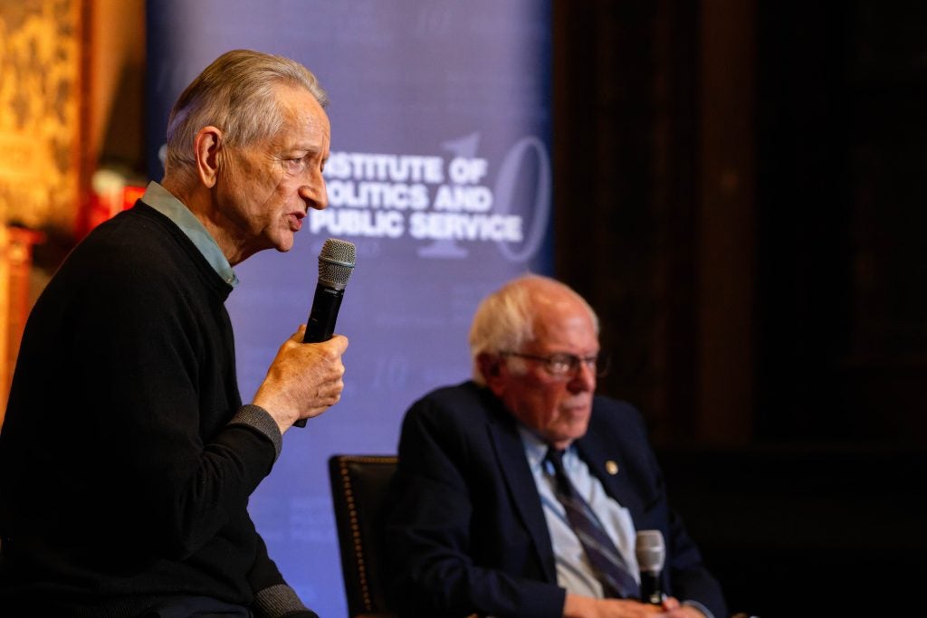Geoffrey Hinton speaks into a mic at an event in Gaston Hall
