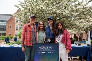 Four women outside in front of a sign for Earth Commons