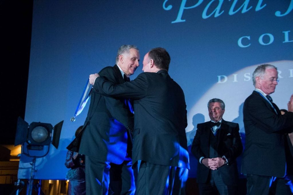 Tagliabue shaking hands on stage and receiving a medal.