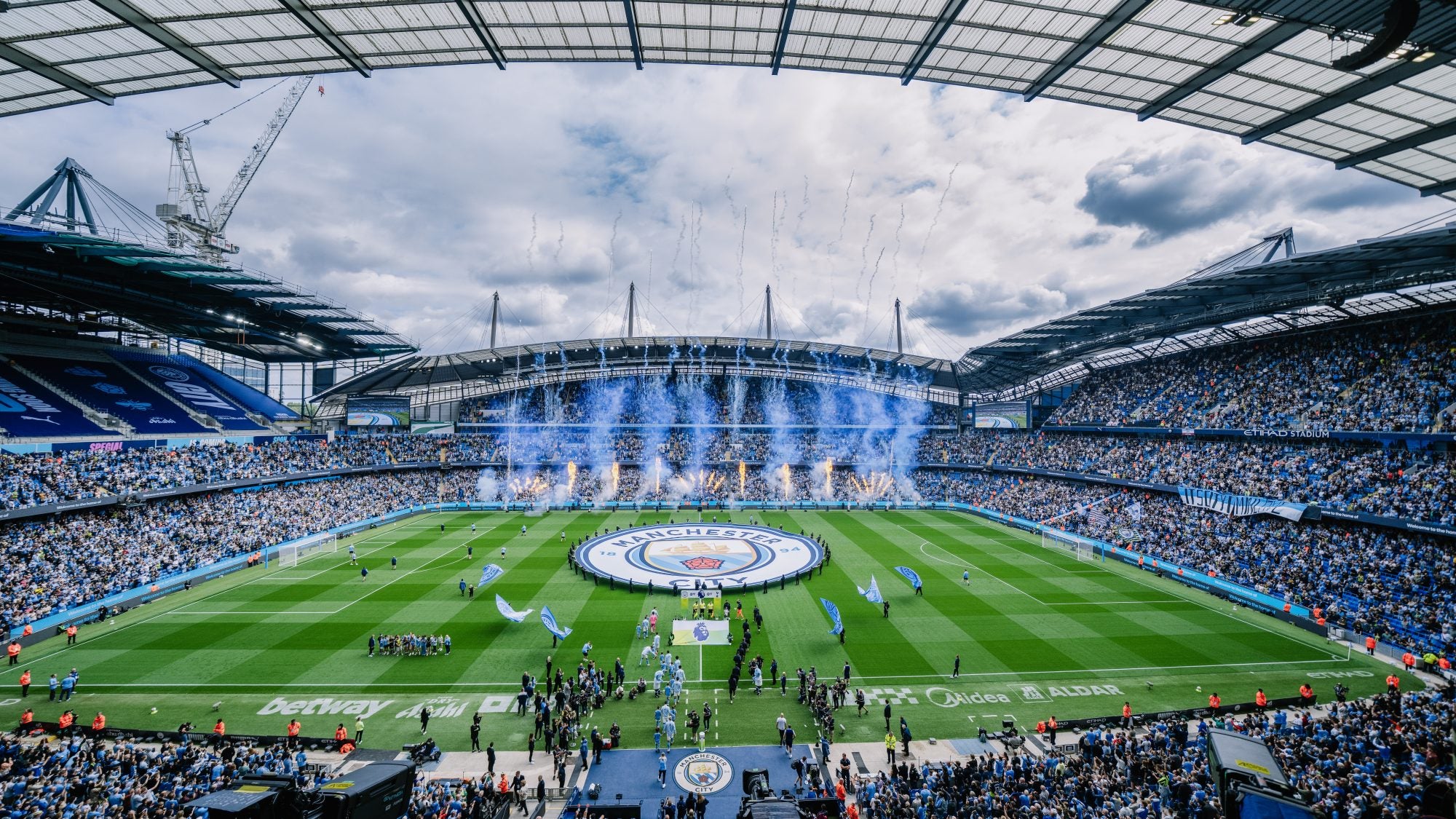 General view inside the stadium as a giant Manchester City crest is displayed on the pitch as blue flares and pyrotechnics are set off ahead of the Premier League match between Manchester City and Tottenham Hotspur at the Etihad Stadium, Manchester, England. Saturday 23rd August 2025. (Photo by Isaac Parkin/Manchester City FC)