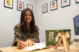 Hispanic woman with brown hair writing in a notebook in an office