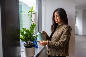 Hispanic woman watering plants by a window