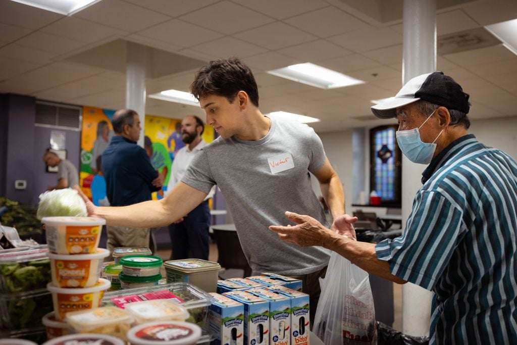 A student helps a client of a food pantry pick out grocery items