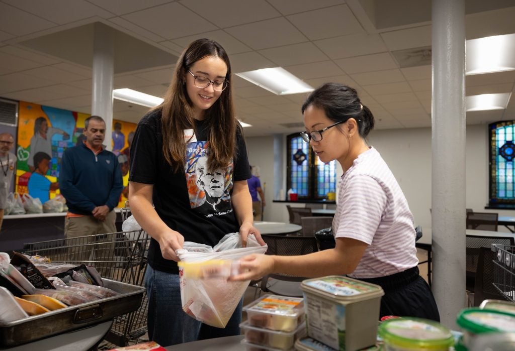 A student helps a woman with her groceries at a food pantry