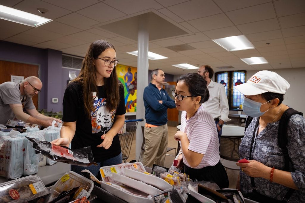 A student helps a woman look for groceries at a food pantry