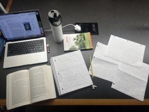 A desk with some papers, a book and computer