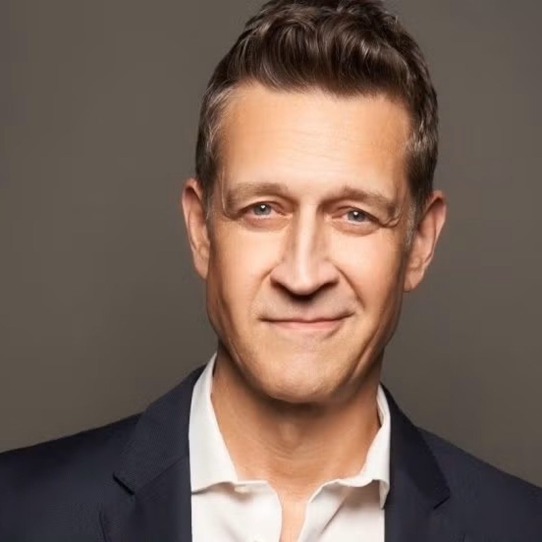 Caucasian man smiling while wearing a suit and white shirt
