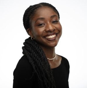 A headshot of a woman wearing a black shirt and necklace and smiling