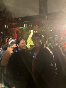 Young man and woman together at night on Healy Lawn with Christmas lights
