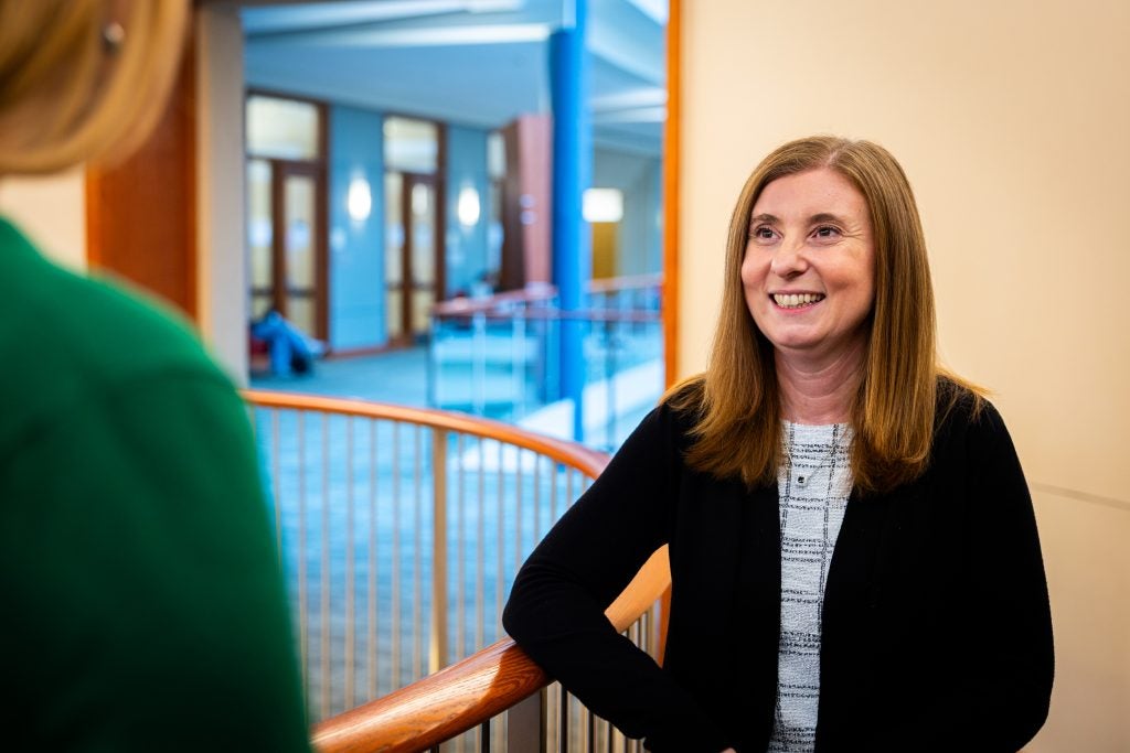 A woman smiles in an academic building