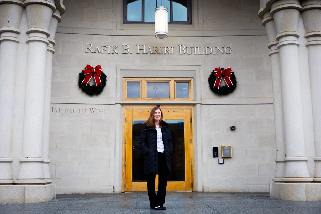 A woman in a suit stands in front of the McDonough School of Business entrance, which has two Christmas wreaths hung up