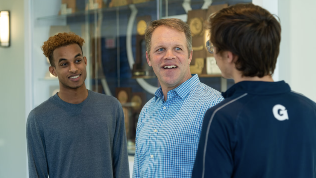 A chaplain speaks to two male student-athletes