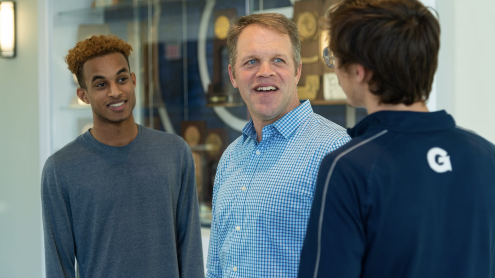 A chaplain speaks to two male student-athletes