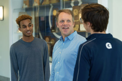 A chaplain speaks to two male student-athletes