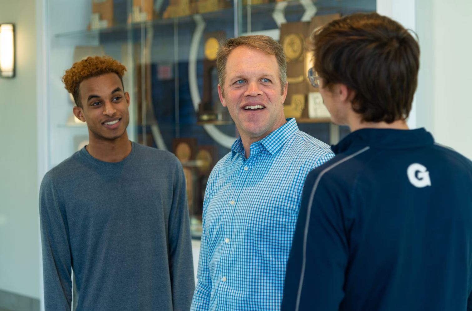 A chaplain speaks to two male student-athletes