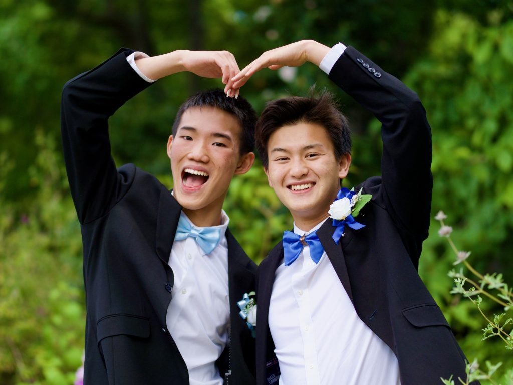 Two young Asian men in tuxedos with bow ties smiling
